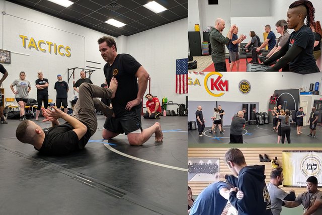 An instructor takes a student to the ground during an adult Krav Maga class, alongside groups drilling palm strikes and close-quarters defences.